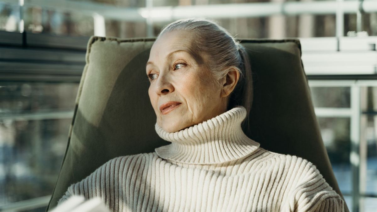 Femme âgée assise dans un fauteuil, chez elle, dans la lumière du jour